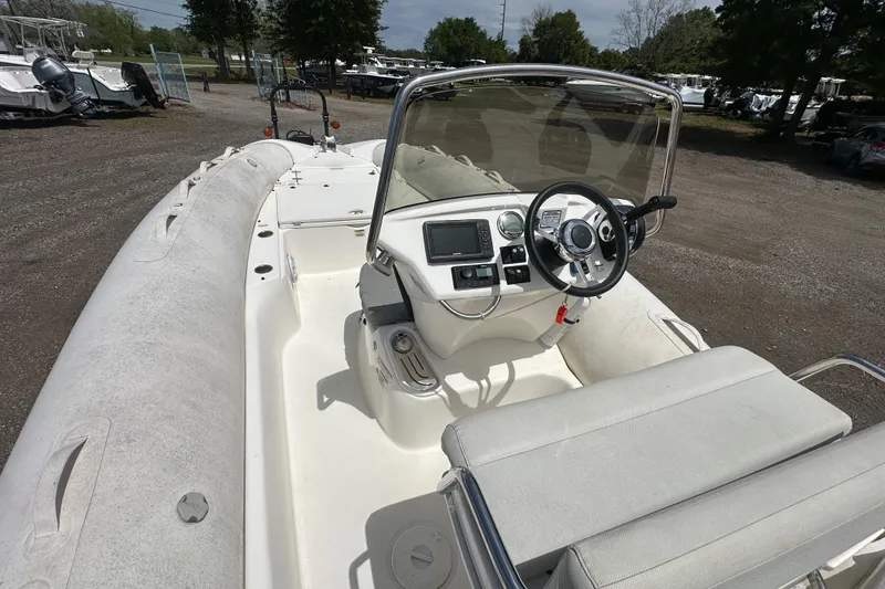 Slide: The Image of 2023 Zodiac N-ZO 680 boat interior with steering console and seating, parked outdoors. - 22