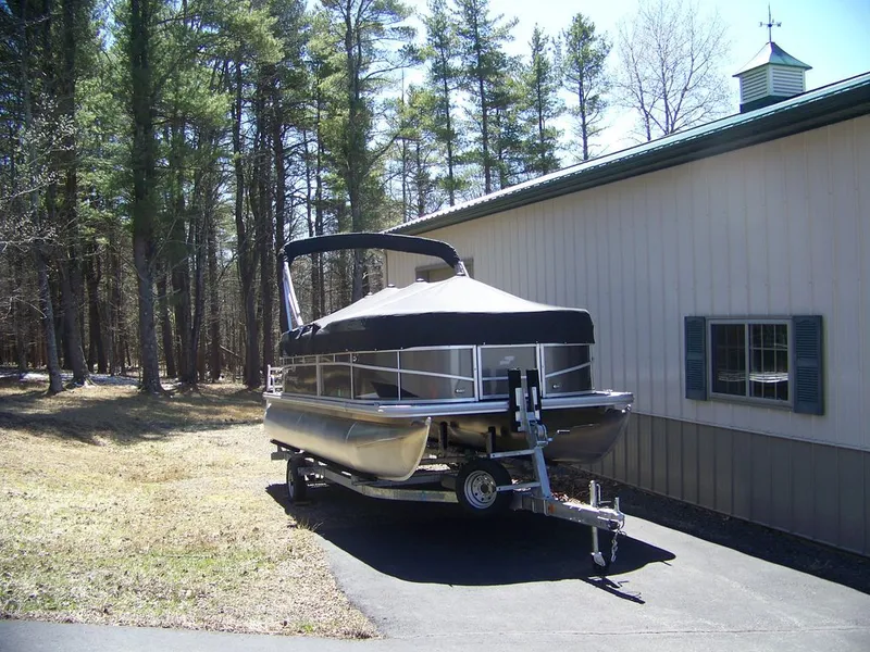 Slide: The Image of 2024 Starcraft LX 20 R pontoon boat on trailer beside building. - 8