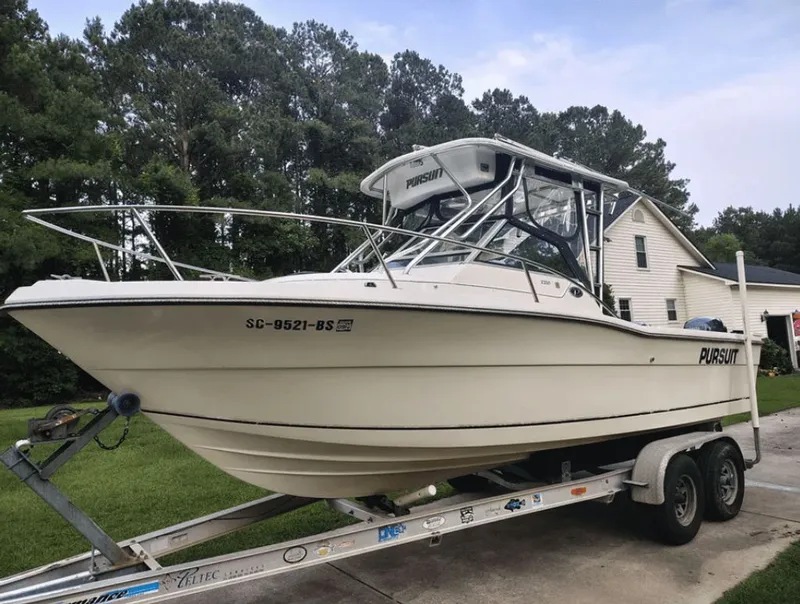 Slide: The Image of 1990 Pursuit 2350 boat on trailer in front of house. - 2
