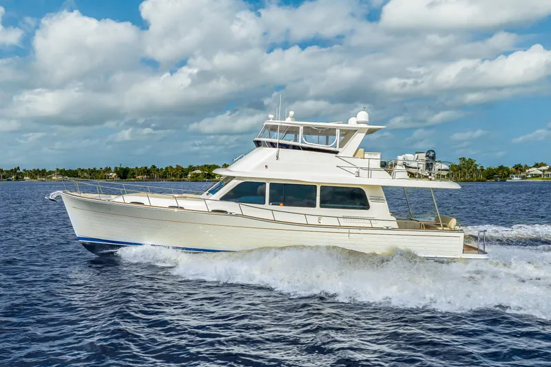The Image of 2023 Grand Banks GB54 yacht cruising on open water under a partly cloudy sky. - 0