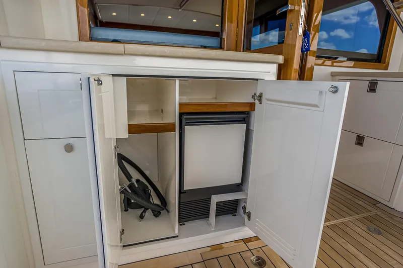Slide: The Image of Open cabinet on 2023 Grand Banks GB54 yacht, revealing storage and equipment. - 14