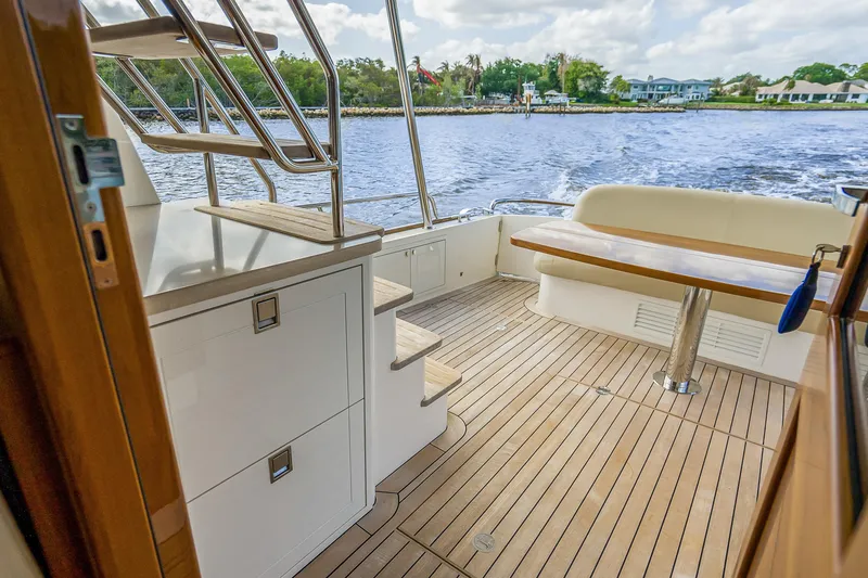 Slide: The Image of 2023 Grand Banks GB54 yacht deck with wooden flooring and seating area. - 15