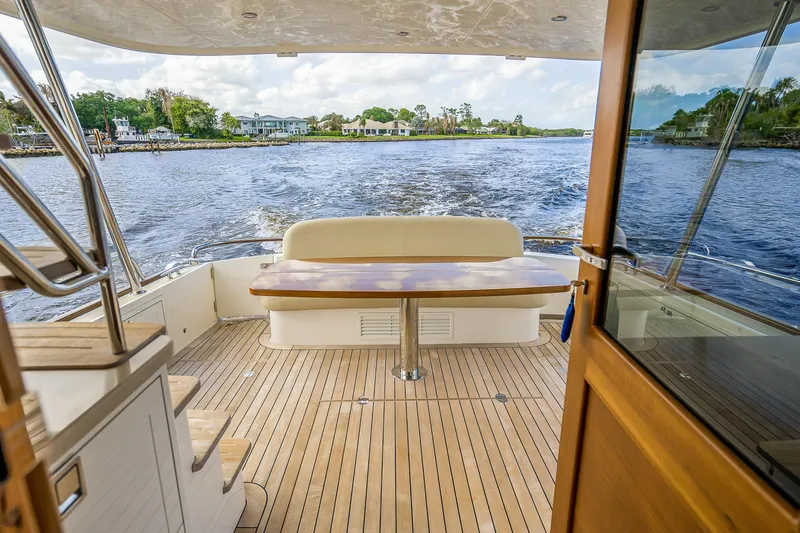 Slide: The Image of 2023 Grand Banks GB54 yacht interior with wooden deck and scenic water view. - 16