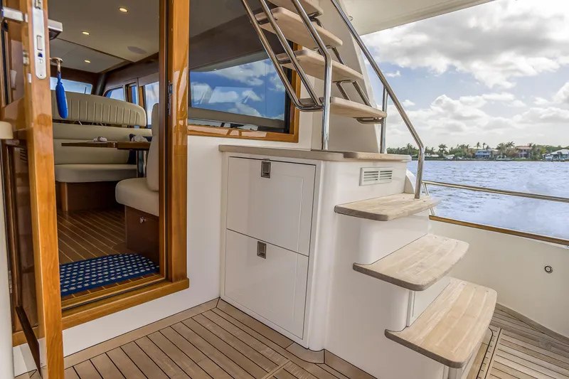 Slide: The Image of 2023 Grand Banks GB54 yacht interior with wooden stairs and seating area. - 17
