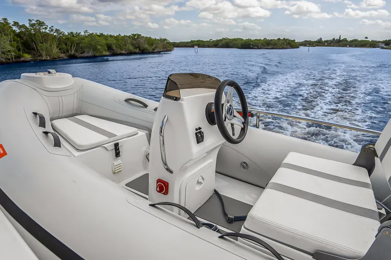 Slide: The Image of 2023 Grand Banks GB54 boat interior with steering wheel, seating, and water view. - 21