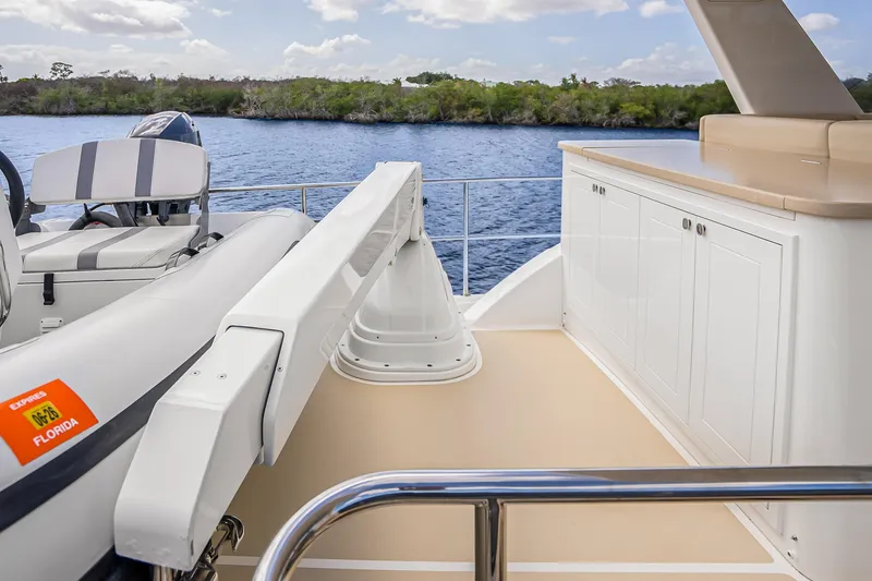 Slide: The Image of 2023 Grand Banks GB54 yacht deck with storage cabinets and tender, cruising on calm waters. - 22