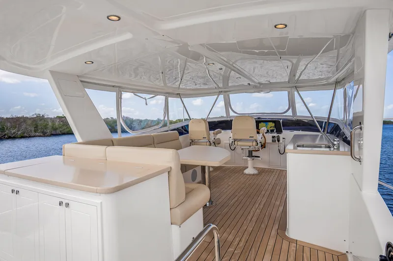 Slide: The Image of Luxurious 2023 Grand Banks GB54 yacht interior with seating, helm, and scenic water view. - 23