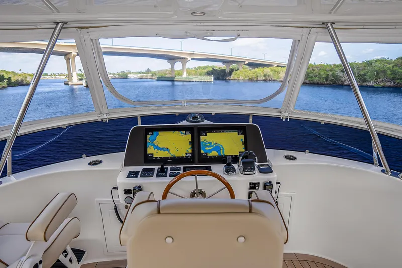 Slide: The Image of 2023 Grand Banks GB54 yacht helm with navigation screens, overlooking a scenic waterway and bridge. - 34