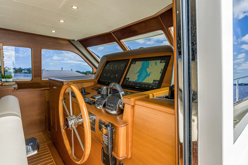 Slide: The Image of Interior helm of 2023 Grand Banks GB54 yacht with navigation screens and wooden steering wheel. - 53