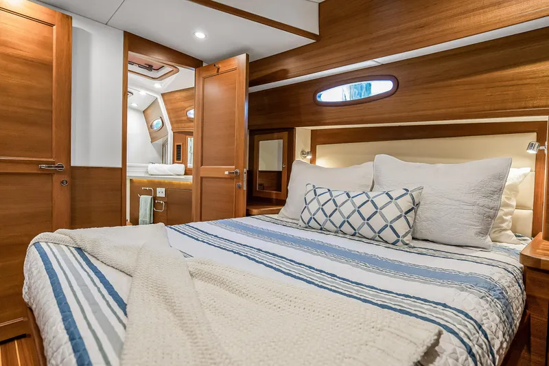 Slide: The Image of Luxurious 2023 Grand Banks GB54 yacht cabin with elegant wood finish and cozy bedding. - 65