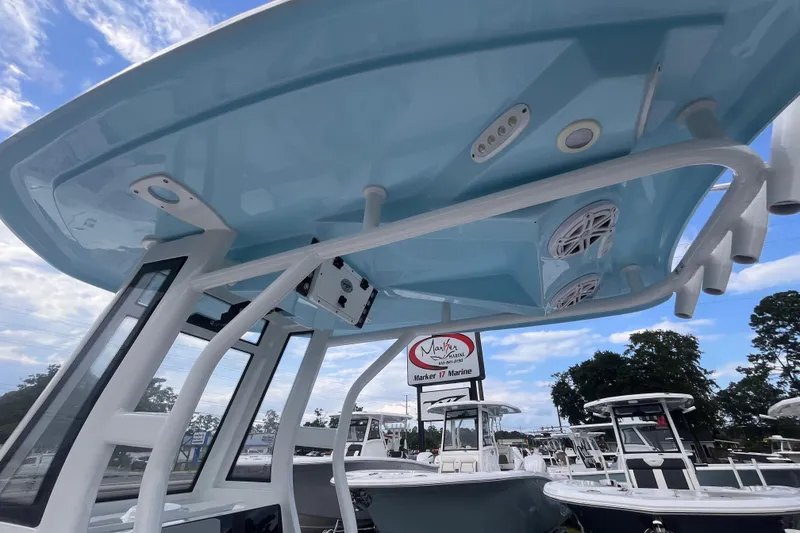 Slide: The Image of 2023 Tidewater 232 CC Adventure boat with blue T-top and speakers at a marine dealership. - 11