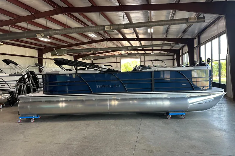 The Image of 2025 Trifecta 24RFCS3 pontoon boat in a spacious indoor showroom. - 1