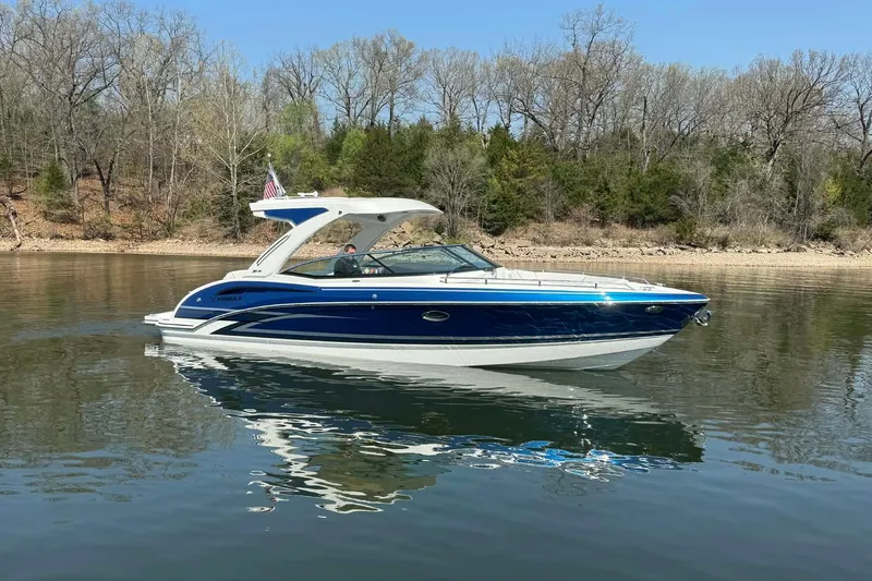 Slide: The Image of 2026 Formula 310 Bowrider I/O boat cruising on a calm lake with wooded shoreline. - 11