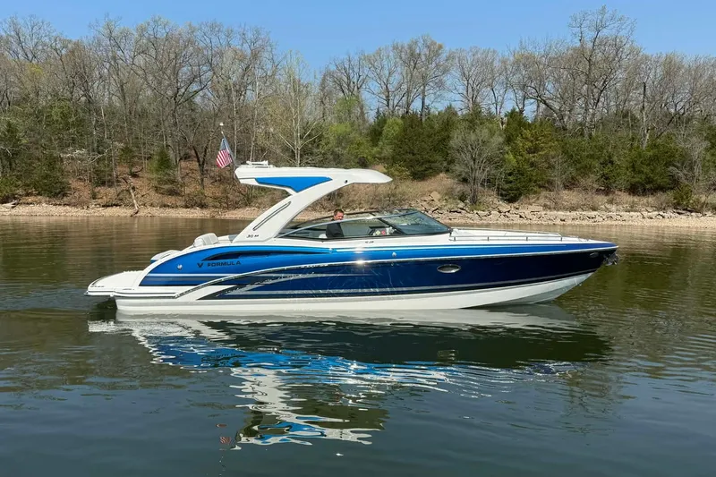 Slide: The Image of 2026 Formula 310 Bowrider I/O boat cruising on a calm lake with forested shoreline. - 13