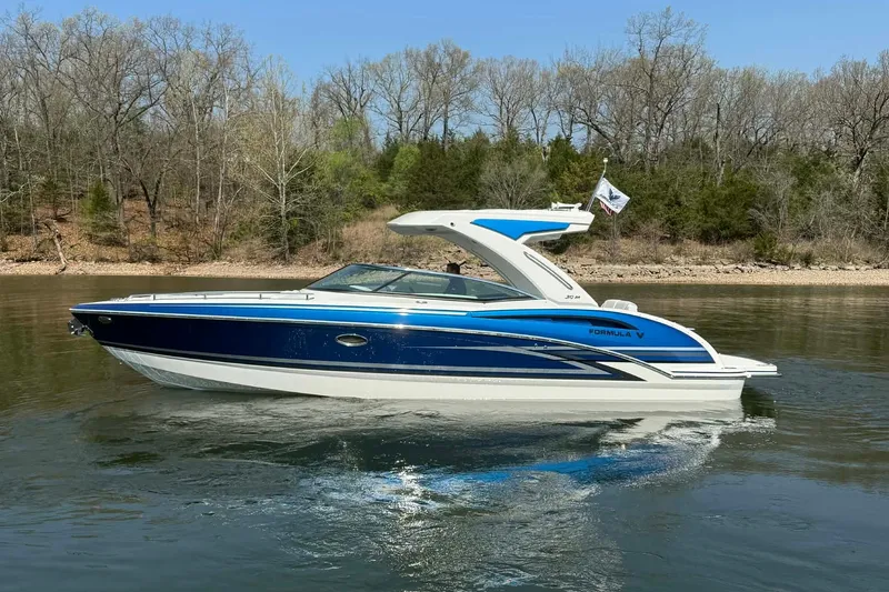 Slide: The Image of 2026 Formula 310 Bowrider I/O boat cruising on a calm lake with forested shoreline. - 6