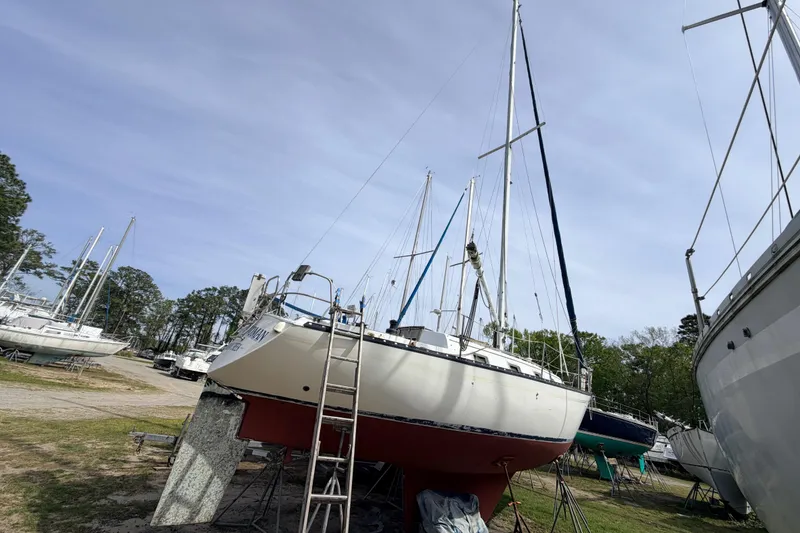 Slide: The Image of 1980 Hunter 37 Cherubini Cutter sailboat on land, surrounded by trees and other boats. - 11