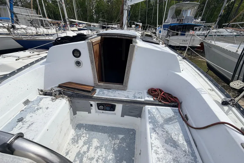 Slide: The Image of 1980 Hunter 37 Cherubini Cutter sailboat cockpit with open cabin door and docked surroundings. - 22
