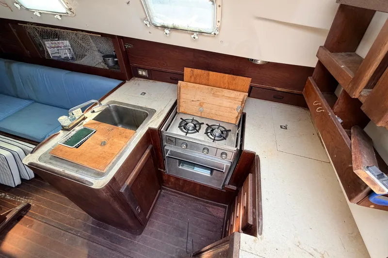 Slide: The Image of 1980 Hunter 37 Cherubini Cutter interior kitchen with stove, sink, and wooden cabinetry. - 31