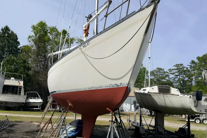 Slide: The Image of 1980 Hunter 37 Cherubini Cutter sailboat on stands, surrounded by trees and other boats. - 6