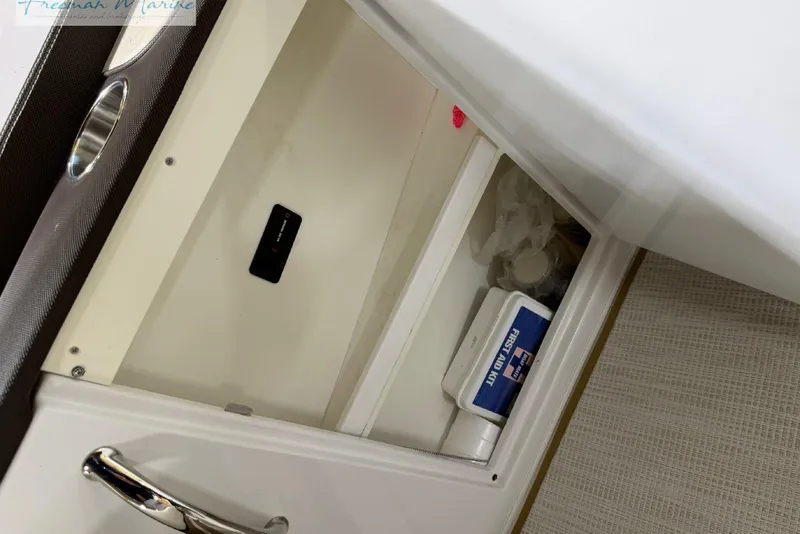 Slide: The Image of Open storage compartment on a 2016 Marker One M25 boat with first aid kit. - 12