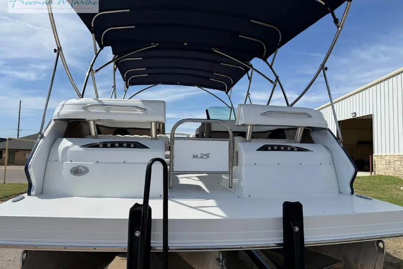 Slide: The Image of 2016 Marker One M25 pontoon boat with canopy, docked outdoors under blue sky. - 25