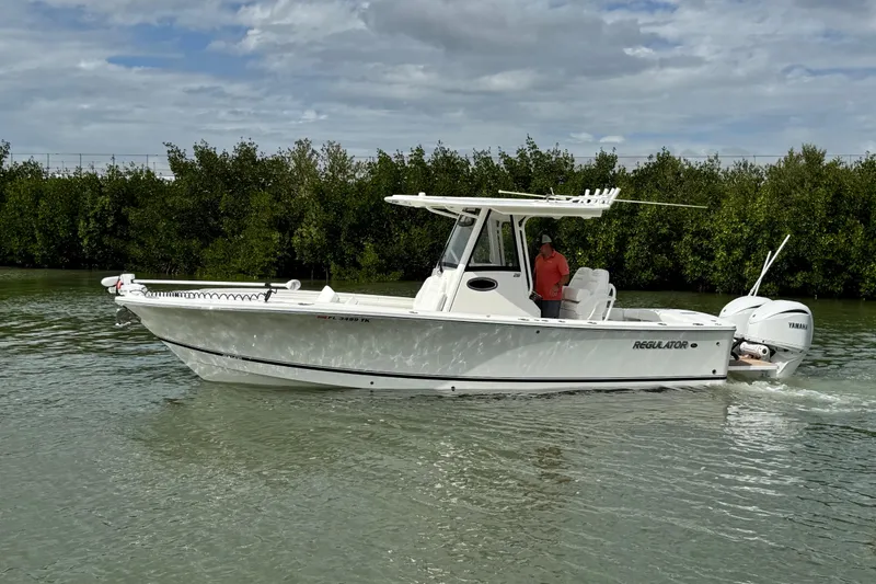 The Image of 2022 Regulator 28 boat cruising on calm water with lush greenery background. - 0