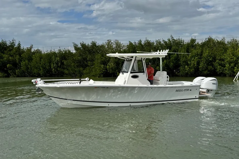 Slide: The Image of 2022 Regulator 28 boat cruising on a calm waterway with lush greenery background. - 11