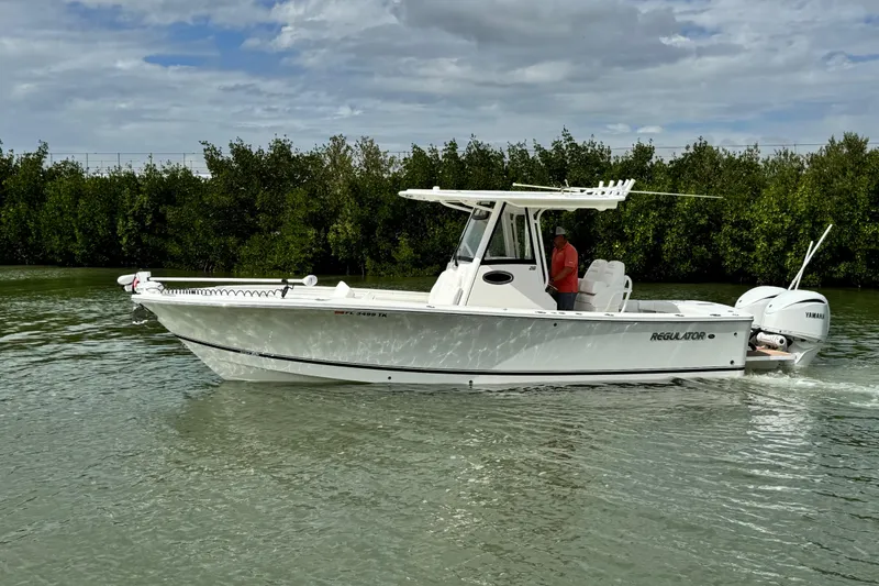 Slide: The Image of 2022 Regulator 28 boat cruising on a calm waterway under a cloudy sky. - 13