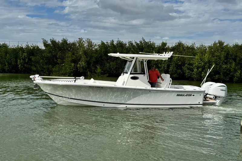 Slide: The Image of 2022 Regulator 28 boat cruising on a calm waterway with lush greenery. - 14