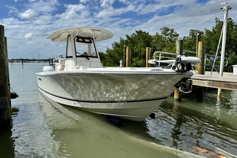 Slide: The Image of 2022 Regulator 28 boat docked on calm water under a partly cloudy sky. - 15
