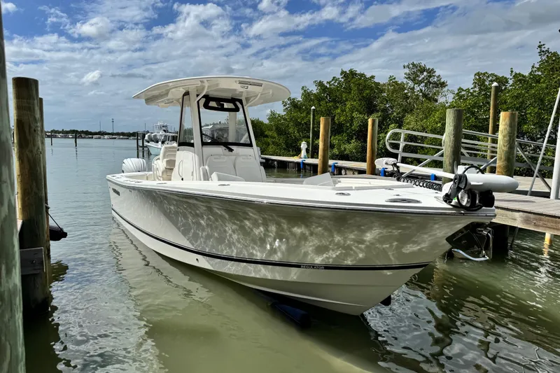 Slide: The Image of 2022 Regulator 28 boat docked in calm waters under a partly cloudy sky. - 18