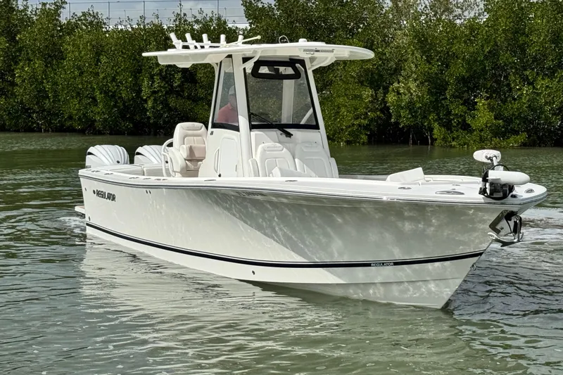 Slide: The Image of 2022 Regulator 28 boat on calm water, surrounded by lush greenery. - 2