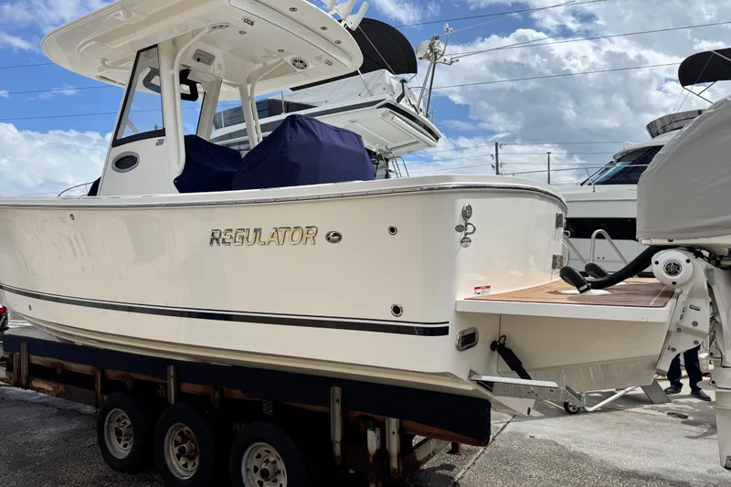 Slide: The Image of 2022 Regulator 28 boat on trailer, white hull, outdoor marina setting. - 22