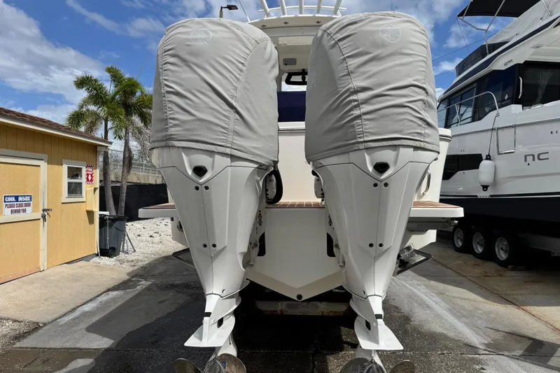Slide: The Image of 2022 Regulator 28 boat with twin covered outboard motors, docked near palm trees. - 24