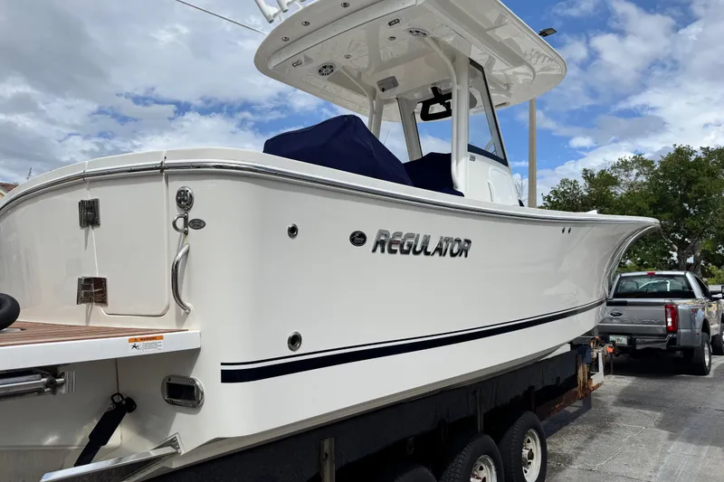 Slide: The Image of 2022 Regulator 28 boat on trailer, white hull, clear sky background. - 25
