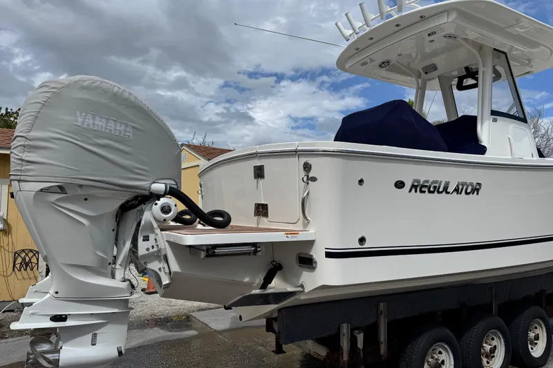 Slide: The Image of 2022 Regulator 28 boat with Yamaha engine cover, parked on a trailer under cloudy skies. - 26
