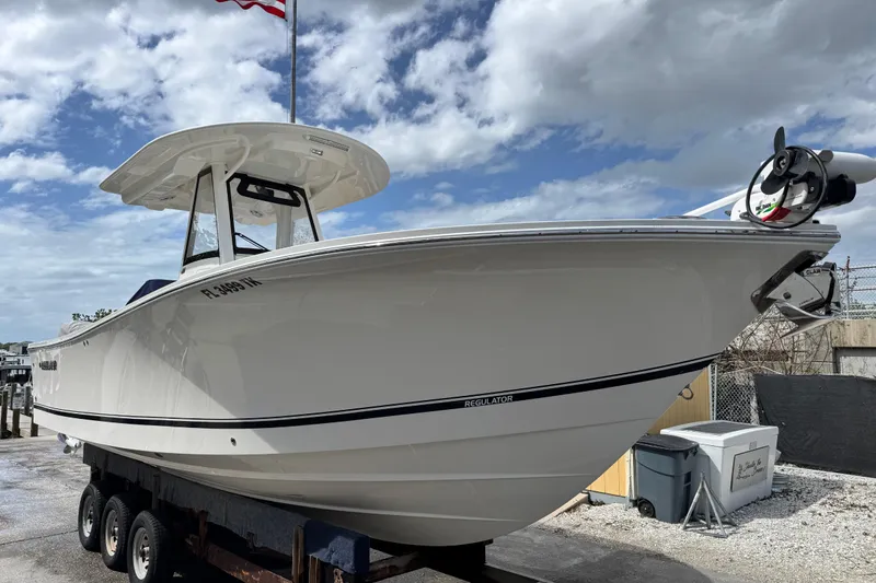 Slide: The Image of 2022 Regulator 28 boat on trailer, under cloudy sky, with American flag in background. - 27