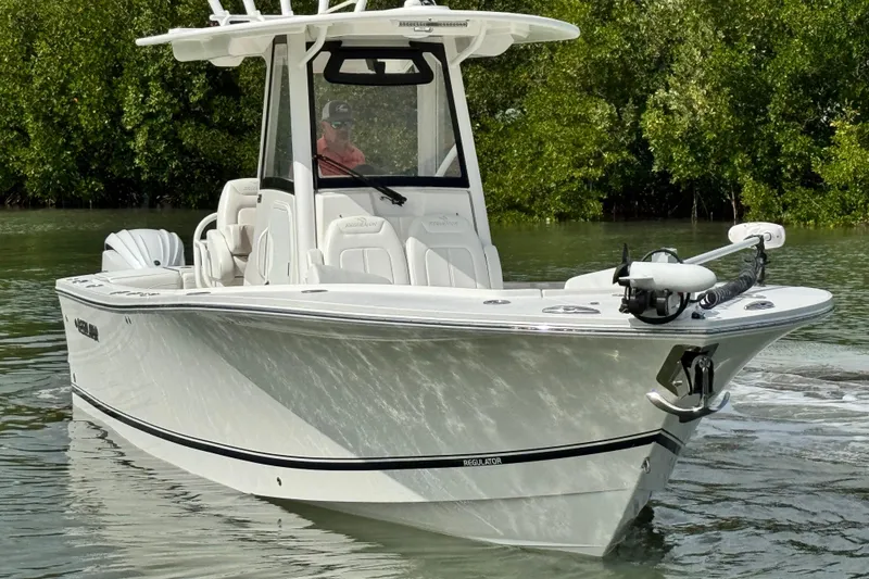 Slide: The Image of 2022 Regulator 28 boat cruising on calm water near lush greenery. - 3