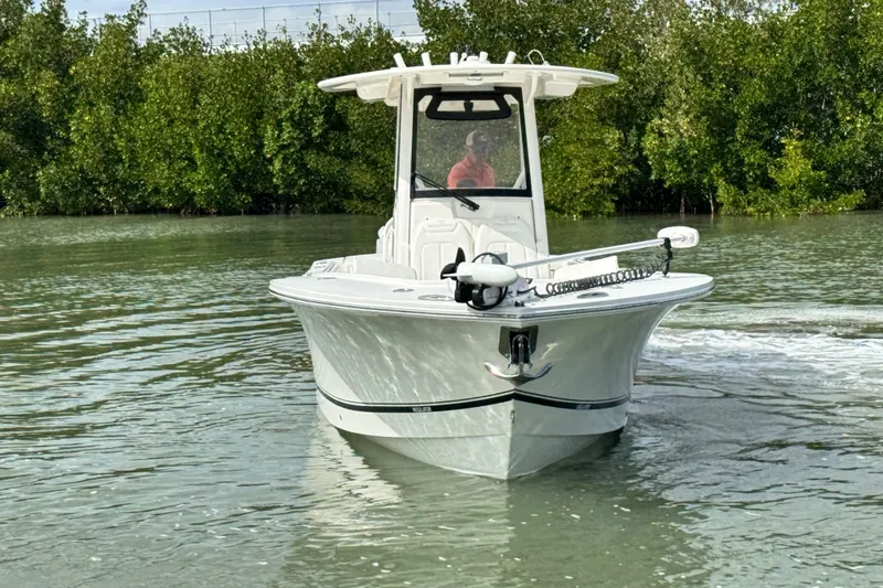 Slide: The Image of 2022 Regulator 28 boat navigating calm waters near lush greenery. - 4