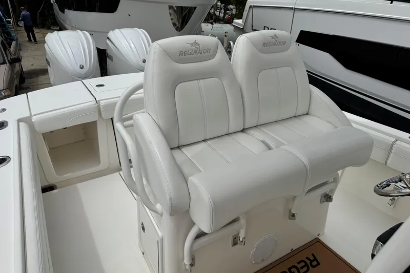 Slide: The Image of 2022 Regulator 28 boat with white cushioned seating and dual outboard engines. - 50