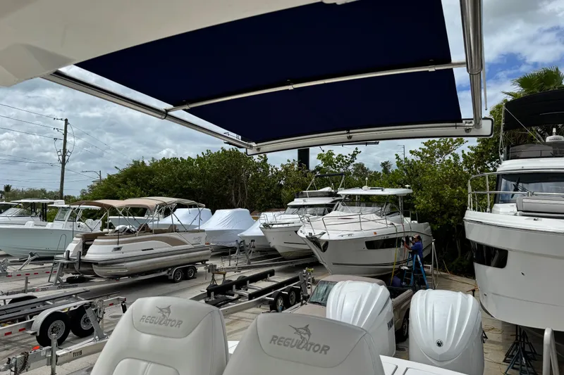 Slide: The Image of 2022 Regulator 28 boat in marina with other vessels, under a blue canopy. - 54