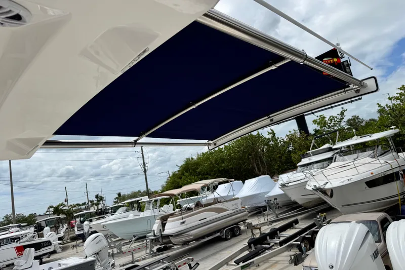 Slide: The Image of 2022 Regulator 28 boat with blue canopy, surrounded by other boats in a marina. - 55