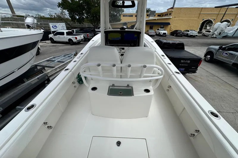 Slide: The Image of 2022 Regulator 28 boat interior with helm, rod holders, and seating in a marina setting. - 64