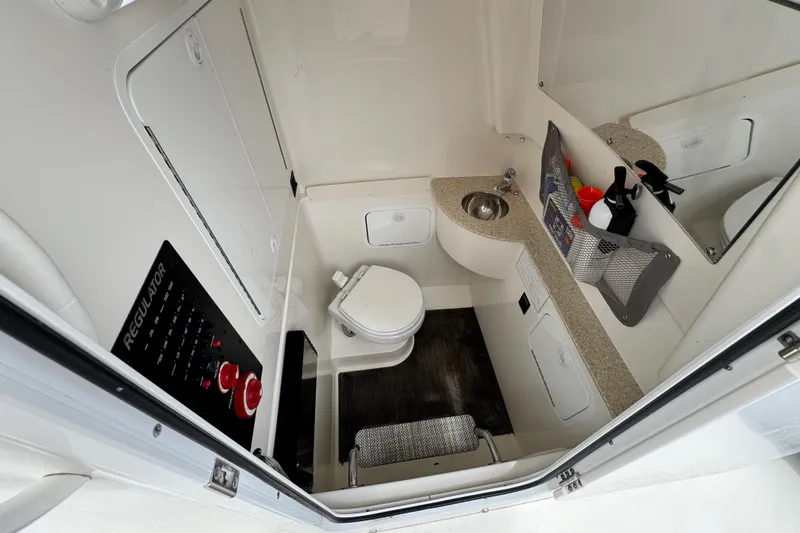 Slide: The Image of 2022 Regulator 28 boat interior with compact bathroom, sink, and storage. - 68