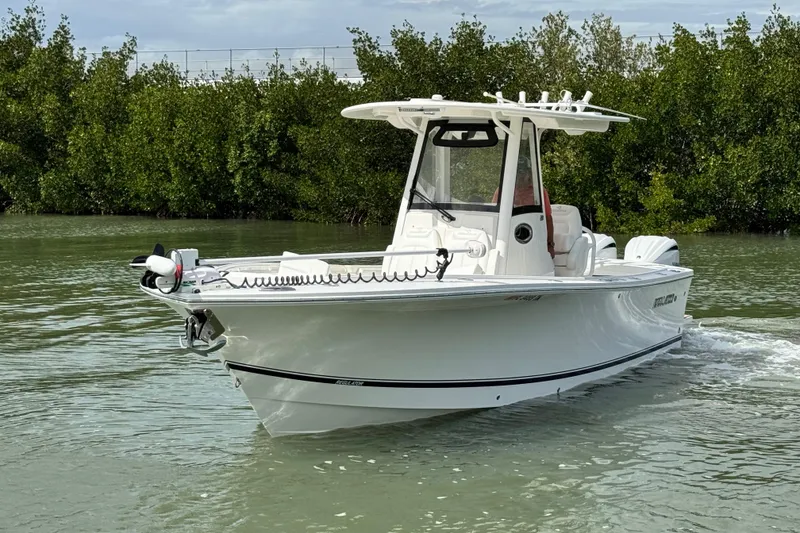 Slide: The Image of 2022 Regulator 28 boat cruising on calm water near lush greenery. - 7