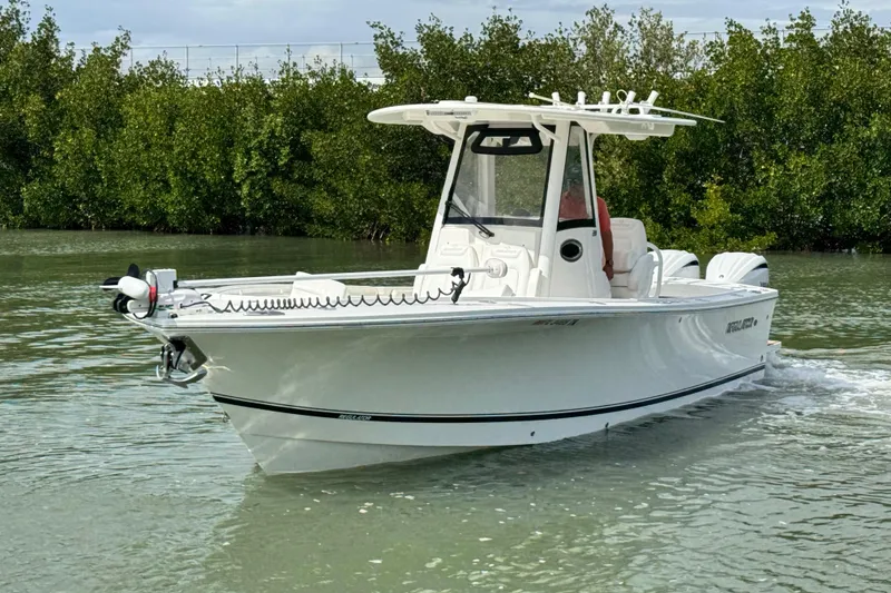 Slide: The Image of 2022 Regulator 28 boat cruising on calm water near lush greenery. - 8