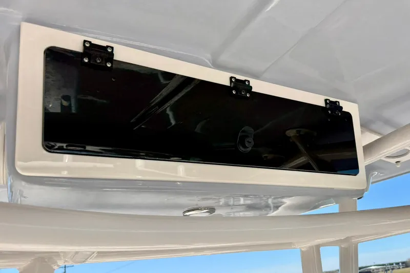 Slide: The Image of 2024 Carolina Skiff 26 Ultra Elite boat storage compartment with black panel and secure latches. - 26