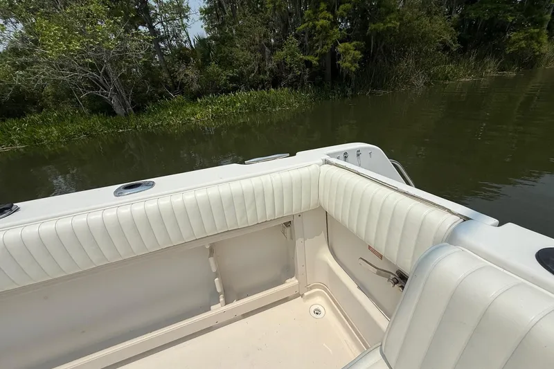 Slide: The Image of 1999 Grady-White Marlin 300 boat interior with white seating near lush shoreline. - 14