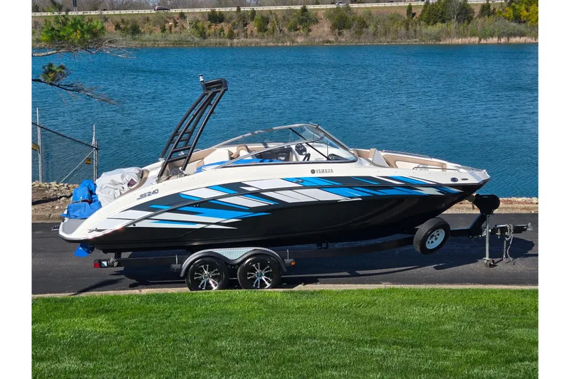The Image of 2011 Yamaha Boats SX240 HO on trailer by a lake, showcasing sleek design. - 0