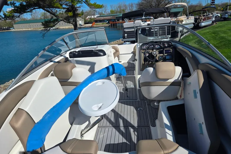 Slide: The Image of 2011 Yamaha Boats SX240 HO interior with seating, steering wheel, and table on a sunny day. - 10